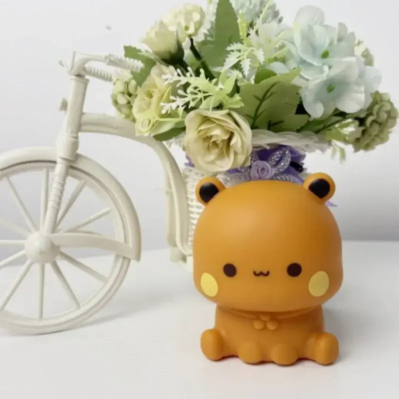 Bubu and Dudu lamp figurine next to a vase of flowers, perfect for adding charm to any room.