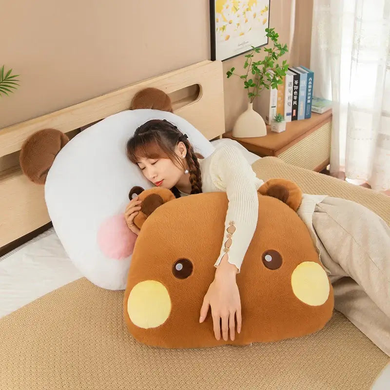 A woman cuddling large Bubu and Dudu plushie pillows on a bed, showcasing comfort and cuteness.